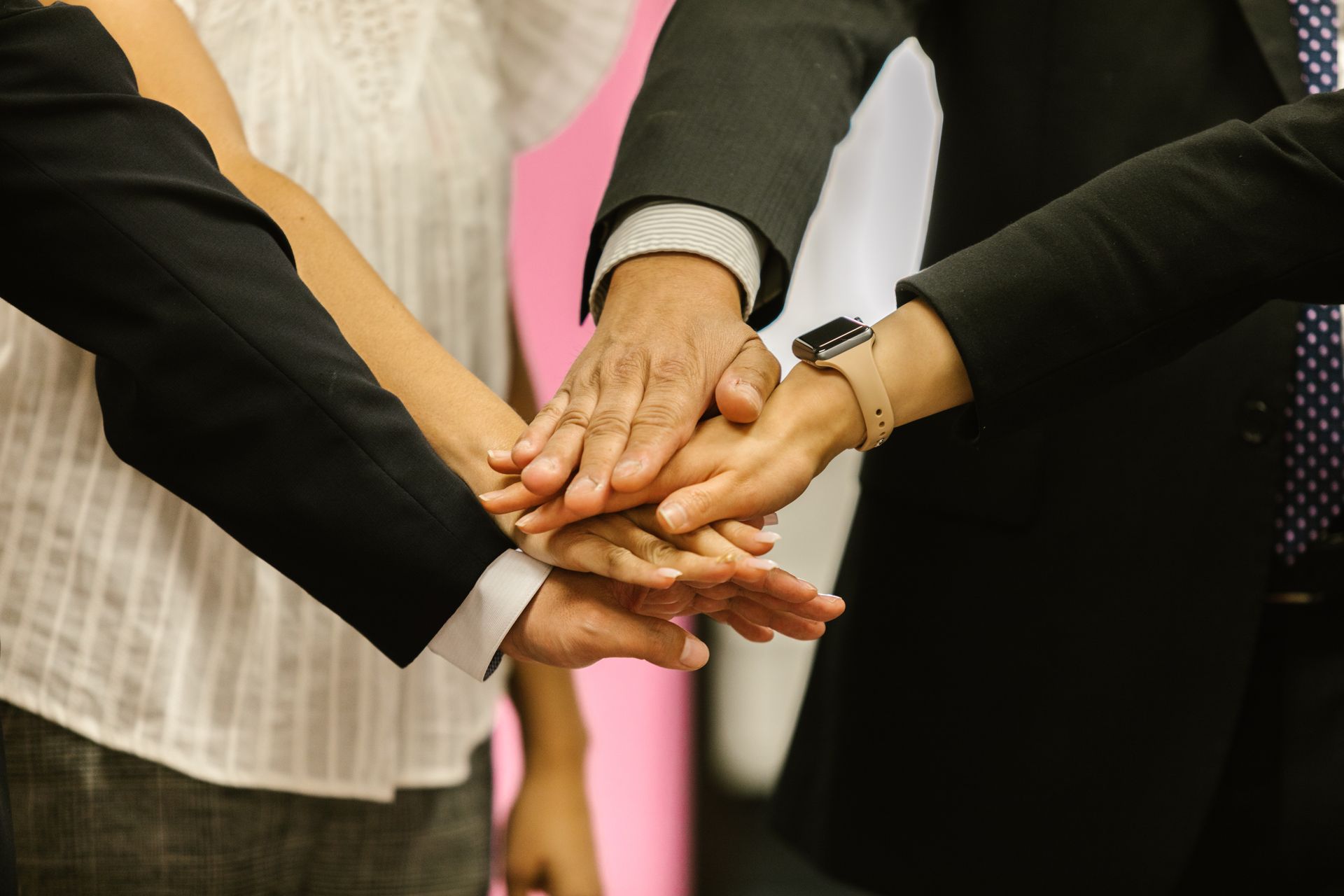 Profesionales con las manos al frente simbolizando trabajo en equipo
